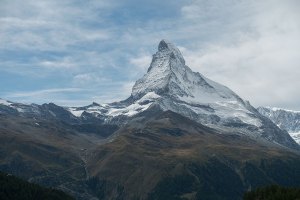 Montaña Matterhorn cubierta de nieve en un paisaje alpino con un cielo nublado.